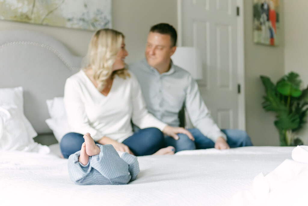 couple pose in bedroom with newborn son 