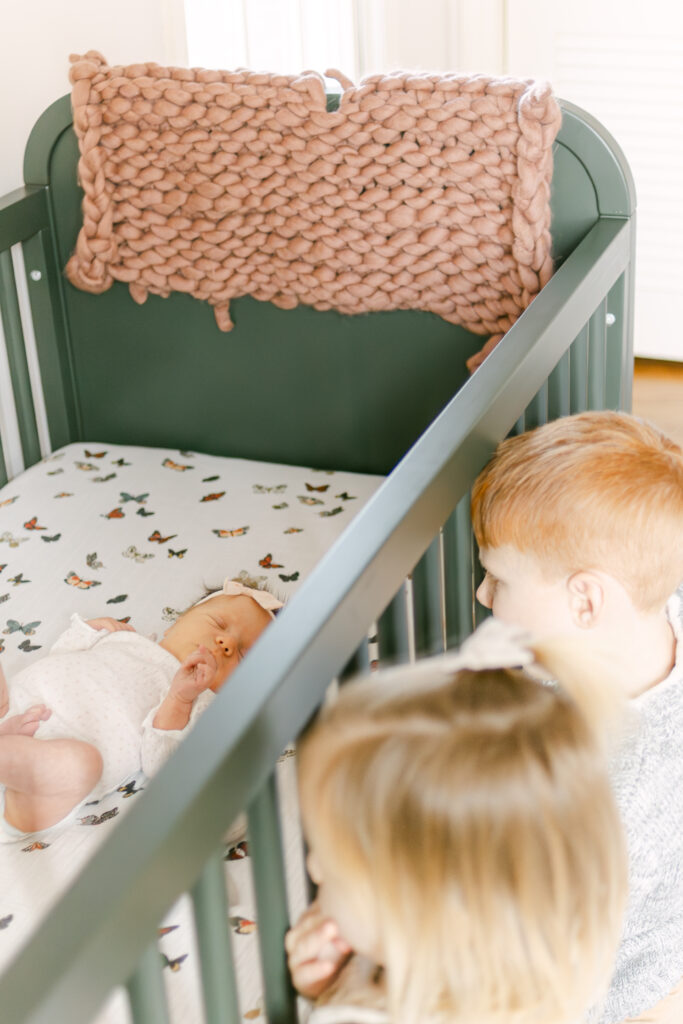 two young siblings look into the crib of their newborn baby sister dayton ohio 