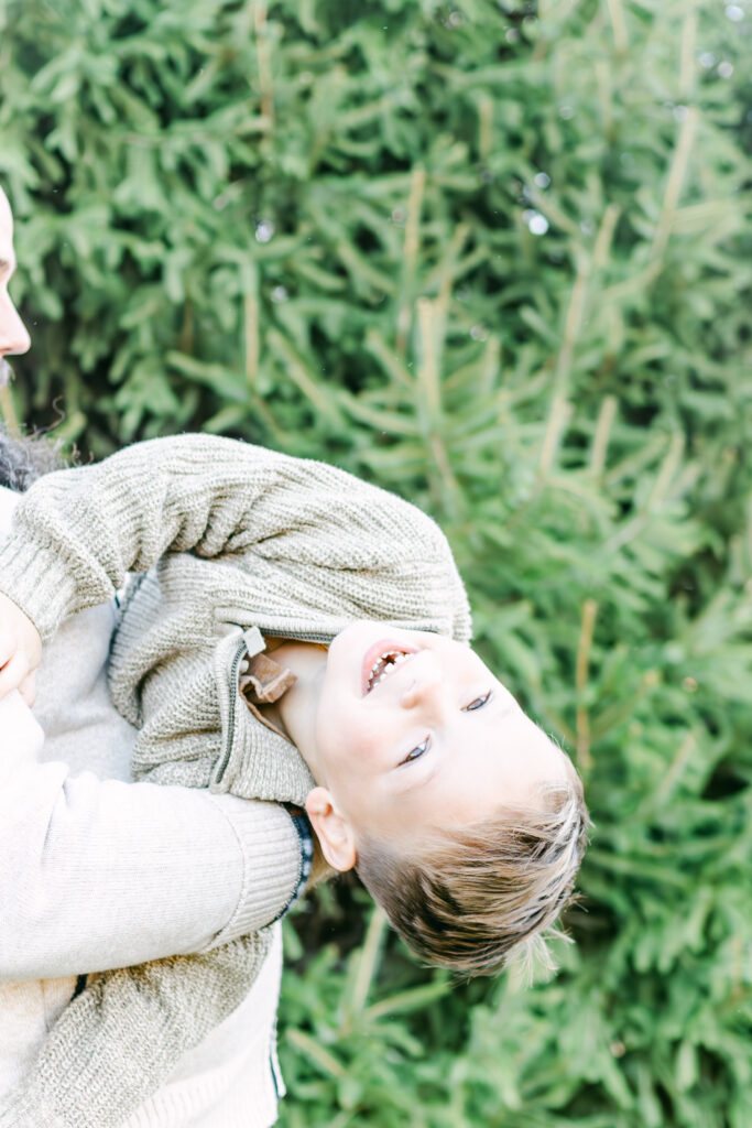 young boy in fathers arms, laughing while dayton family photographer takes picture