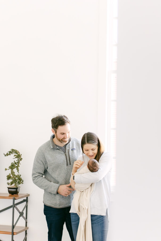 new parents hold infant daughter posing for professional photos