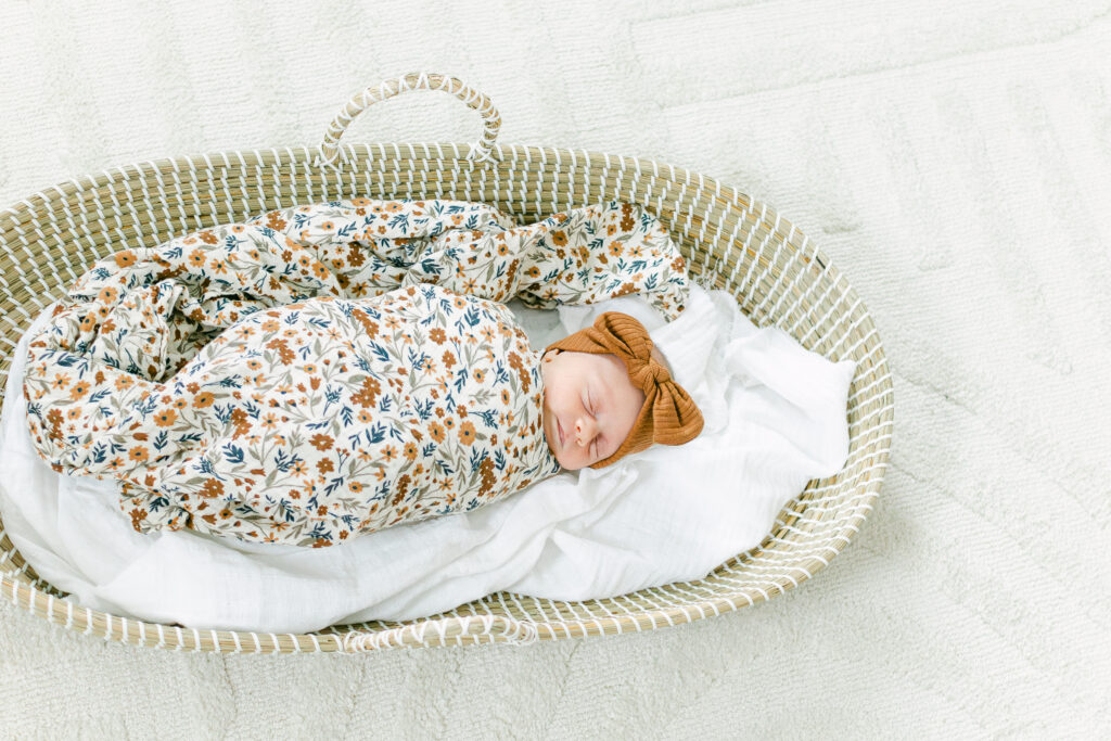 newborn baby girl swaddled in moses basket