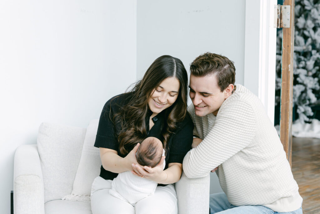 mom and dad smiling down at newborn baby boy at cincinnati newborn studio photography session