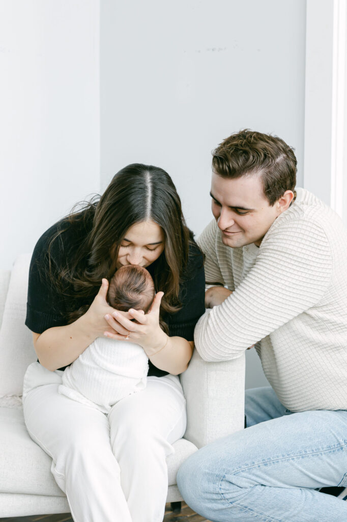 dad smiling as mom is kissing newborn baby boy for cincinnati newborn photography session