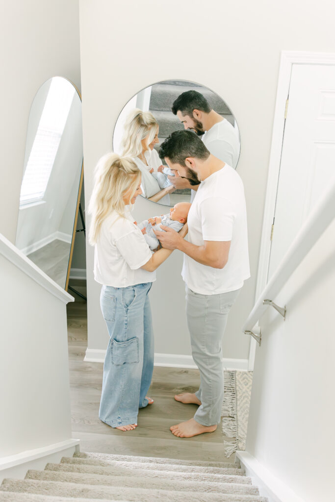 family of three newborn session in cincinnati ohio home with mom hold baby boy and dad is smiling down at baby