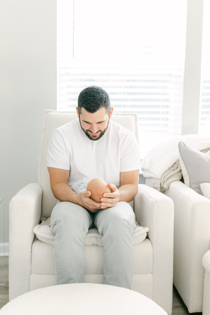 dad smiling down at baby boy adn he is hold him for morrow newborn photography session